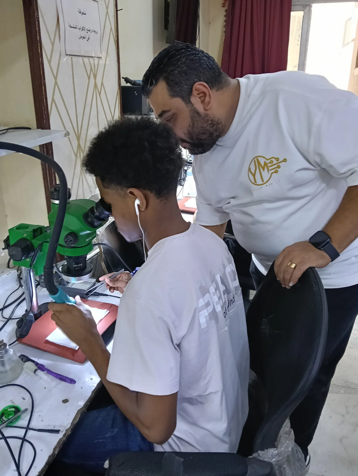 مدرب من يلا موبايل يتابع تطبيق متدرّب على طاولة الصيانة